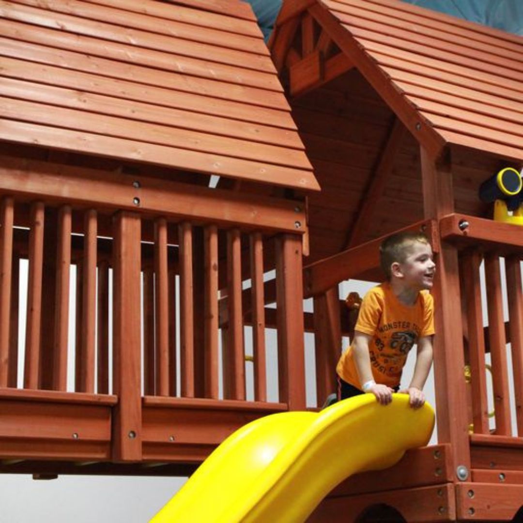 Young child playing on a yellow slide on a play set. 
