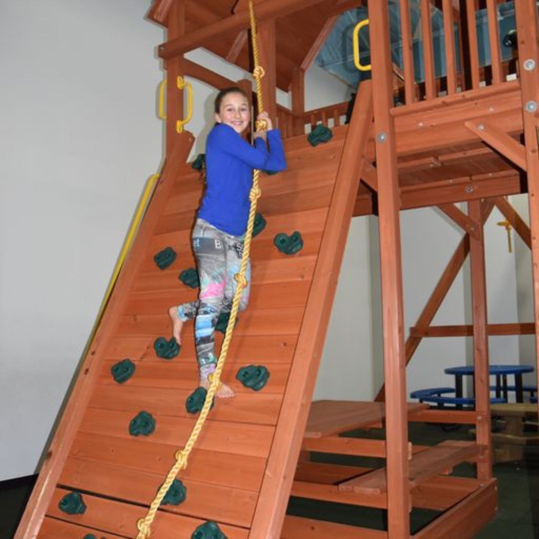 Young girl climbing up a Superior Play Systems play set. 