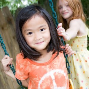 one girl pushes another on a swing