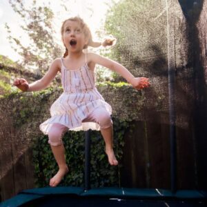 girl with pigtails jumps on trampoline