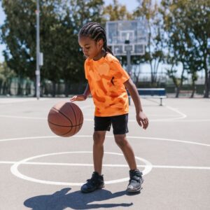 kid wearing an orange shirt dribbles basketball 