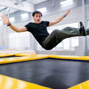 person bounces in sitting position on trampoline 