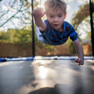 kid flies in superman pose above trampoline