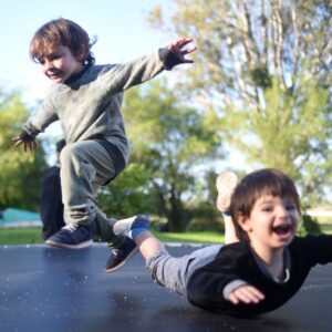 boys jump on trampoline and land on their stomachs 